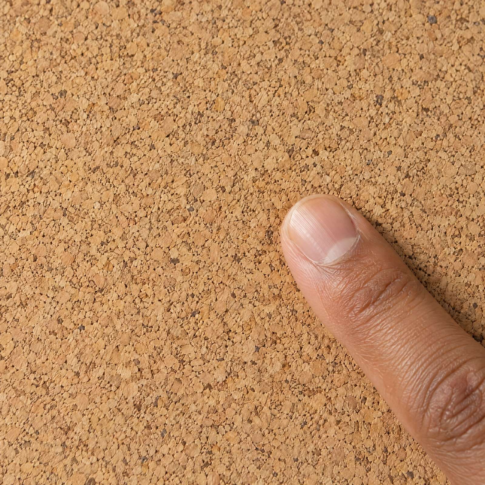 A fingertip on the fine-grain cork surface, close up.
