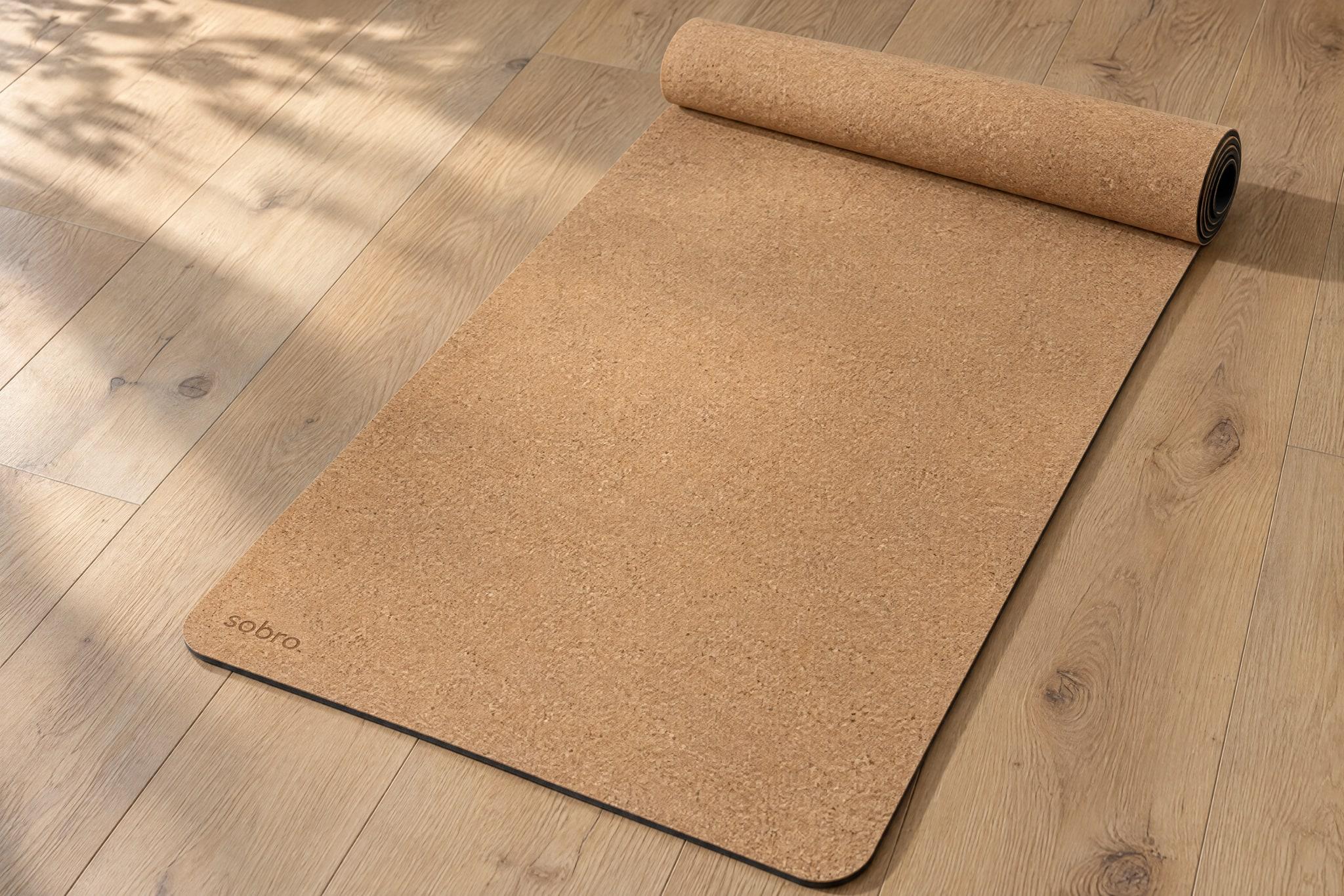 The cork mat on an oak floor, its far end loosely rolled, a small mark etched in one corner.