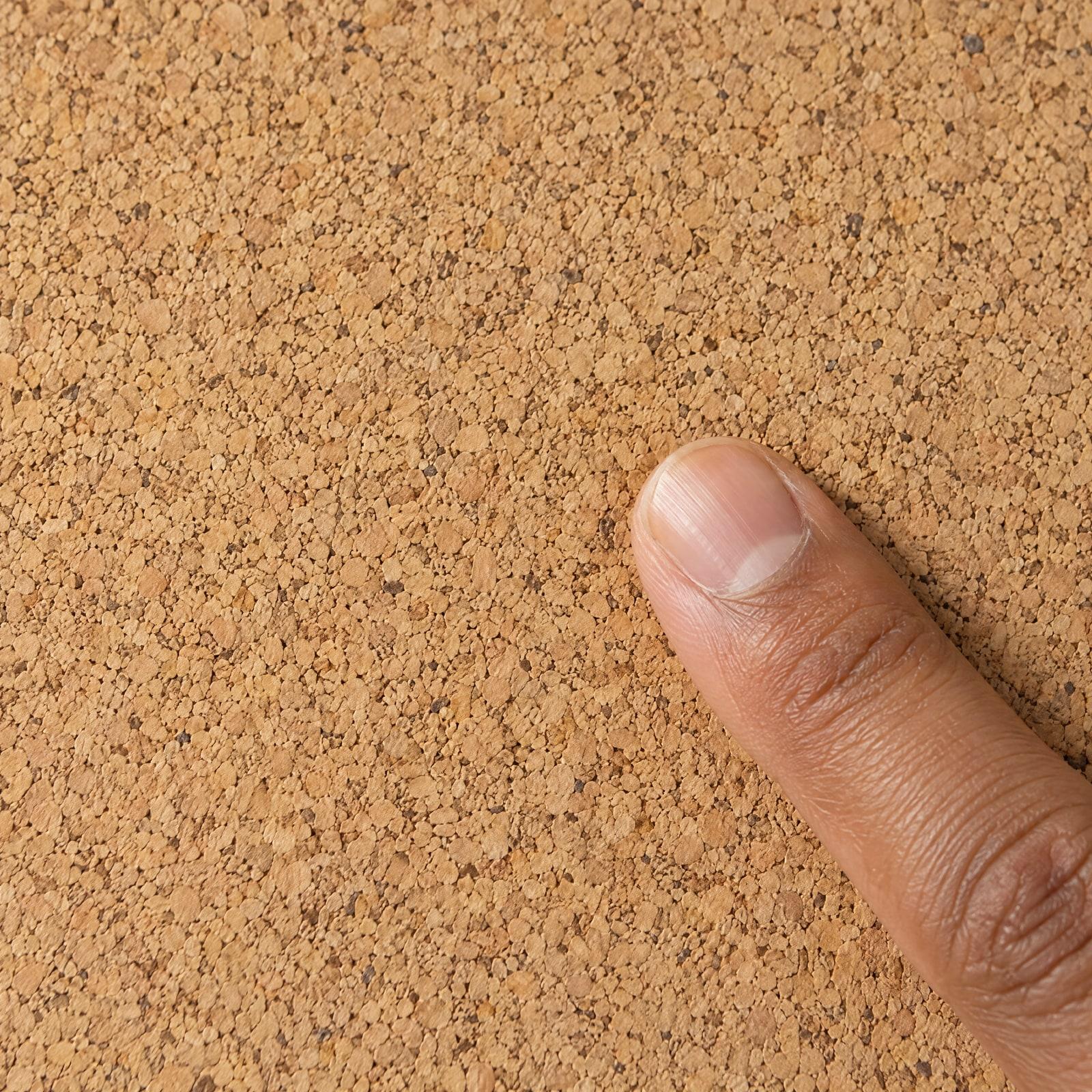 A fingertip on the fine-grain cork surface, close up.